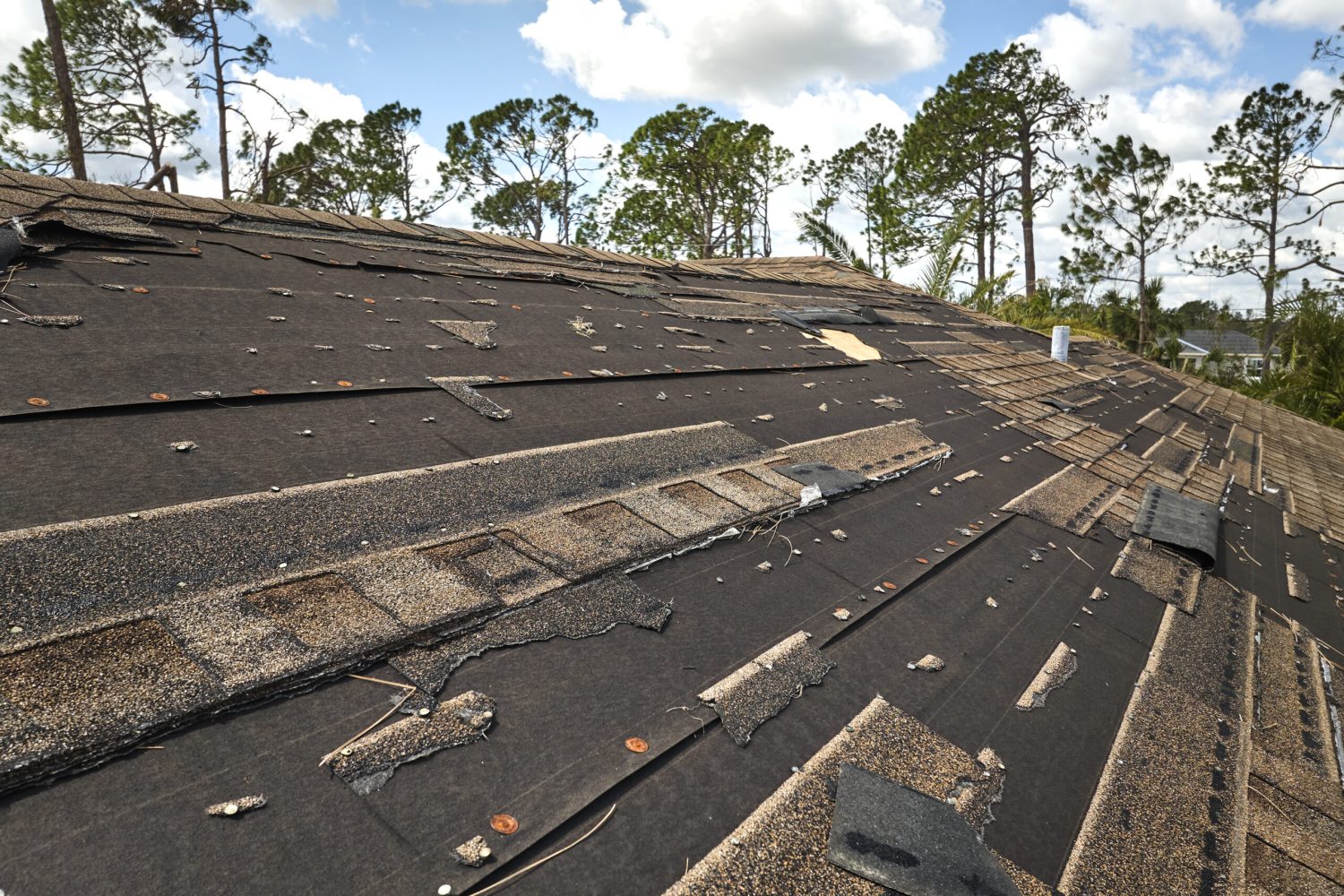 Damaged house roof with missing shingles after hurricane Ian in Florida. Consequences of natural disaster.