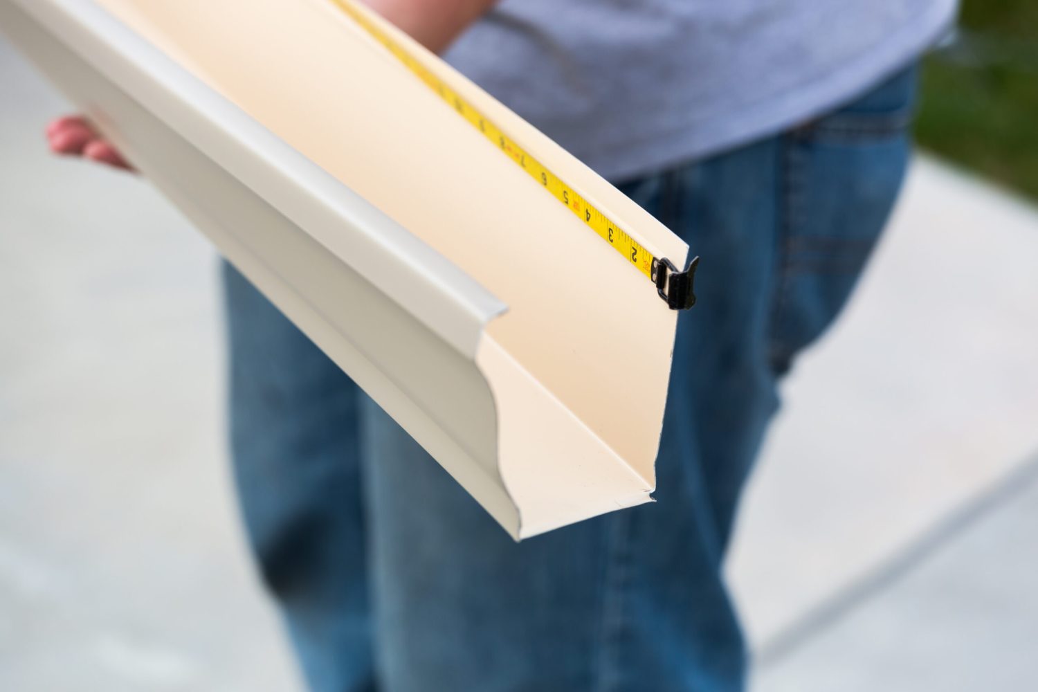 Worker Measuring An Aluminum Rain Gutter Feeding Through Seamless Shaping Machine.